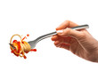Female hand holds a fork with spaghetti pasta and splash of tomato sauce.