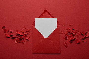 Wall Mural - top view of blank white letter in envelope with paper cut hearts on red background