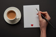© LIGHTFIELD STUDIOS - cropped view of woman writing on empty greeting card with red heart sign near cup of coffee