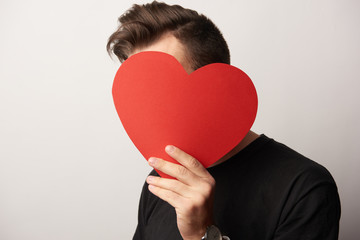 man with obscure face holding empty paper cut heart card