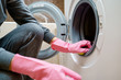 Image of woman 's hand in pink rubber glove washing washing machine