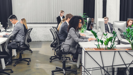 Wall Mural - side view of professional multiethnic young business people working with digital devices in open space office