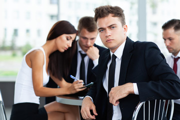 Wall Mural - Smiling Businessman posing while colleagues talking together in office.