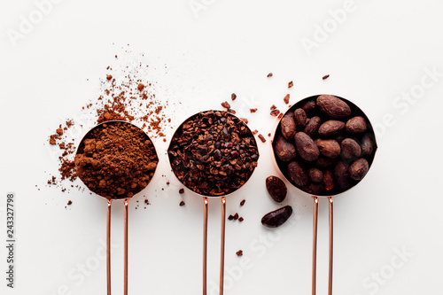 Cuadros en Lienzo Rose gold measuring cups of cocoa beans, cacao nips and cocoa powder on a white