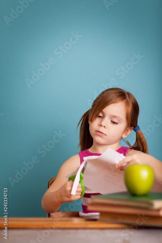 Fotografie, Obraz Girl in School Desk Cutting Paper Craft - Room for Text