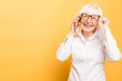 Phone conversation. Positive aged woman smiling while talking on the phone isolated over yellow background.
