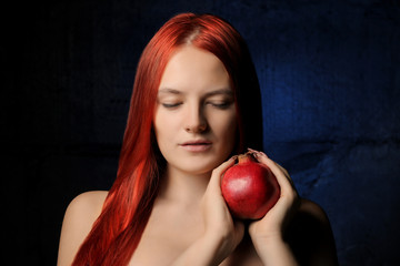 Wall Mural - portrait of beautiful girl with red hair and pomegranate fruit on the background of blue wall. different poses.