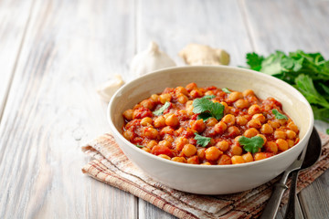 Spicy Chickpea curry Chana Masala in bowl on wooden table. Traditional Indian dish. Selective focus.