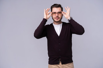 Wall Mural - Young happy man in eyeglasses posing confidently with big smile on gray background.