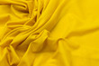 Close-up texture of natural orange or yellow fabric or cloth in same color. Fabric texture of natural cotton, silk or wool, or linen textile material. Yellow canvas background.