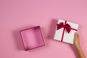 Congratulations background. Hand open empty present gift box on pastel pink background, top view