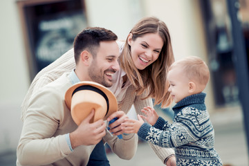 Wall Mural - Smiling young parents and their child in city