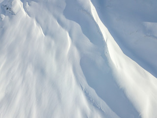 Wall Mural - Aerial view of snow covered terrain in mountain area. Mountains in central Switzerland. Alps with snow in beautiful light with shadow and sun.