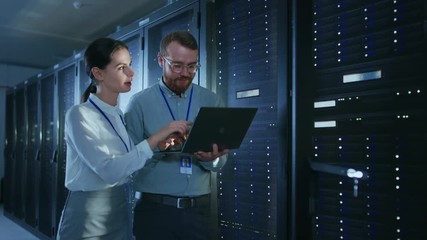 Aufkleber - Bearded IT Technician in Glasses with Laptop Computer, Beautiful Young Engineer Colleague are Talking in Data Center while Working Next to Server Racks. Running Diagnostics or Doing Maintenance Work