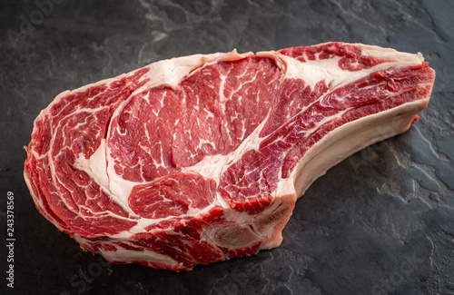 Fotomural raw cowboy steak on stone background, prime rib eye on bone