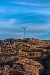 Wall Mural - View of a wind turbine on top of mountains, dramatic sunset sky