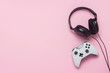 Headphones and gamepad on a pink background. The concept of the game on the console, entertainment, leisure, online games. Flat lay, top view.