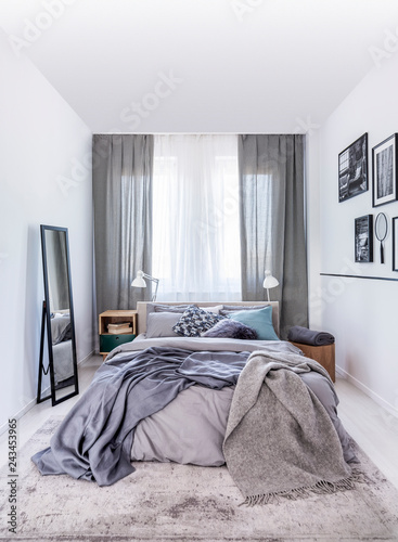 Mirror Next To Bed With Grey Sheets In White Bedroom