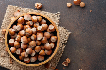 Hazelnuts in wooden bowl on textured background