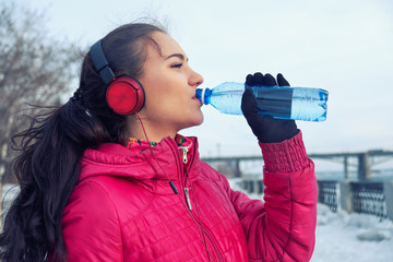 Drinking during sport. Young woman drinking water after run