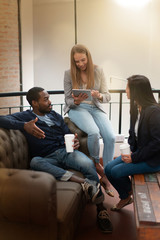 Attractive co workers talking sitting on sofa with tablet