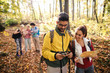 © Dusan Petkovic - Cute couple looking at compass. Woman holding map while the rest hikers standing in the background and looking at map. Autumn time.