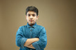 © IndiaPix - Portrait of serious boy standing with crossed arms over color background