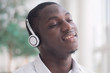 © 9nong - Modern African man listening to music headsets; portrait of happy smiling Black African man enjoying digital mobile music player device; African man young adult model