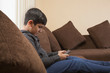 © IndiaPix - Boy sitting on sofa using smart phone in living room