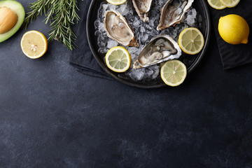 Wall Mural - Fresh oysters in a plate with ice on black background