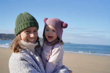 Portrait of mother and young daughter on beach in winter