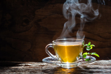 Wall Mural - Hot tea in glass teapot and cup with steam on wood background