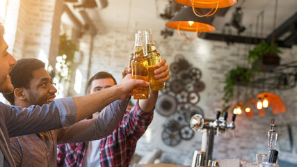 Wall Mural - Friends having rest in bar, clinking beer bottles