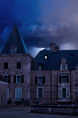 Poster - Old castle with illuminated window at dusk.