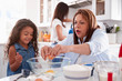 © Monkey Business - Young girl making a cake in the kitchen with her grandmother, mum in the background, selective focus