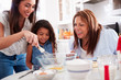 © Monkey Business - Young girl making a cake in the kitchen with her mum and grandmother, close up