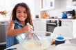 © Monkey Business - Young Hispanic girl making cake mix in the kitchen on her own, smiling, close up