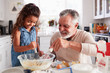 © Monkey Business - Young Hispanic girl and her grandad whisking cake mixture together at the kitchen table, close up