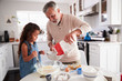 © Monkey Business - Young girl preparing cake mixture with her grandfather at the kitchen table, close up