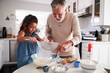 © Monkey Business - Young girl preparing cake mixture with her grandfather at the kitchen table, close up