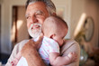© Monkey Business - Hispanic grandfather holding his baby grandson, head and shoulders, close up
