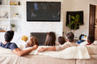 © Monkey Business - Back view of three generation Hispanic family sitting on the sofa watching TV