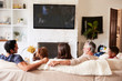 © Monkey Business - Back view of three generation Hispanic family on the sofa watching TV, grandad looking at adult son
