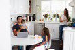 © Monkey Business - Young Hispanic family in their kitchen, dad holding baby, mum cooking at the hob