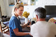 © Monkey Business - Back view of female healthcare worker measuring the blood pressure of senior man during a home visit
