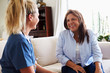 © Monkey Business - Female healthcare worker sitting on the sofa with a middle aged woman during a home health visit