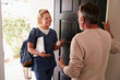 © Monkey Business - Senior man opening his front door to a female healthcare worker making a home health visit