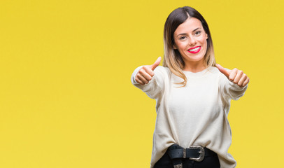 Young beautiful woman casual white sweater over isolated background approving doing positive gesture with hand, thumbs up smiling and happy for success. Looking at the camera, winner gesture.