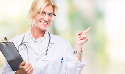 Sticker - Middle age blonde doctor woman holding clipboard over isolated background very happy pointing with hand and finger to the side