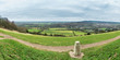 Panorama taken from Box Hill in the Surrey Hills, England, UK, with a trig point in the foreground and farms, fields, the town of Dorking and the village of Brockham in the background.